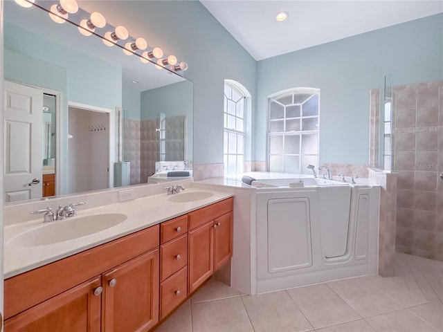 bathroom with tile patterned flooring, double vanity, a sink, and a bath