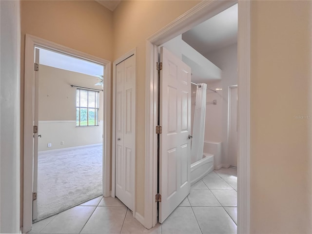 hallway with light carpet and light tile patterned floors