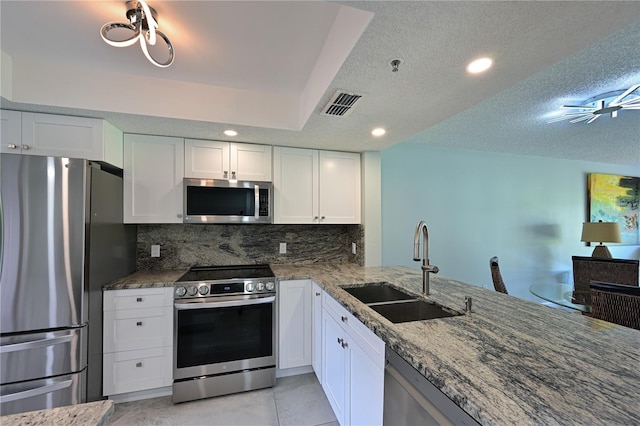 kitchen with stainless steel appliances, tasteful backsplash, visible vents, a sink, and dark stone countertops