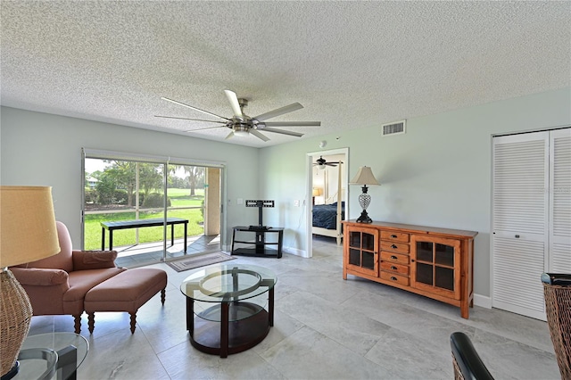 living area with visible vents, ceiling fan, a textured ceiling, and baseboards