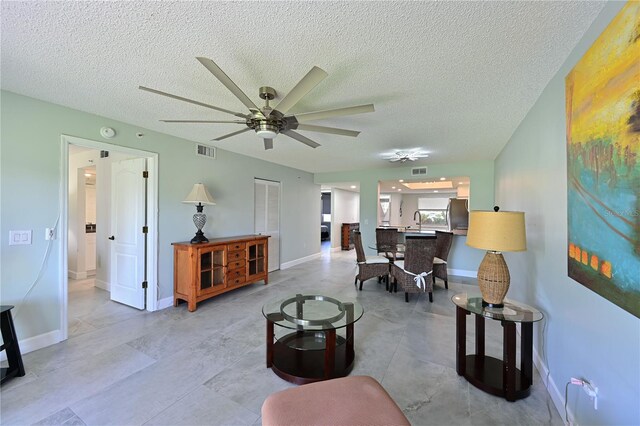 living room with baseboards, visible vents, and a ceiling fan