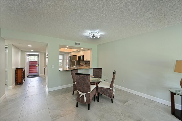 dining room with baseboards, visible vents, and a textured ceiling