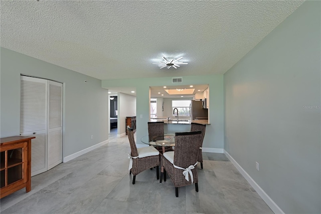 dining space featuring visible vents, a textured ceiling, and baseboards