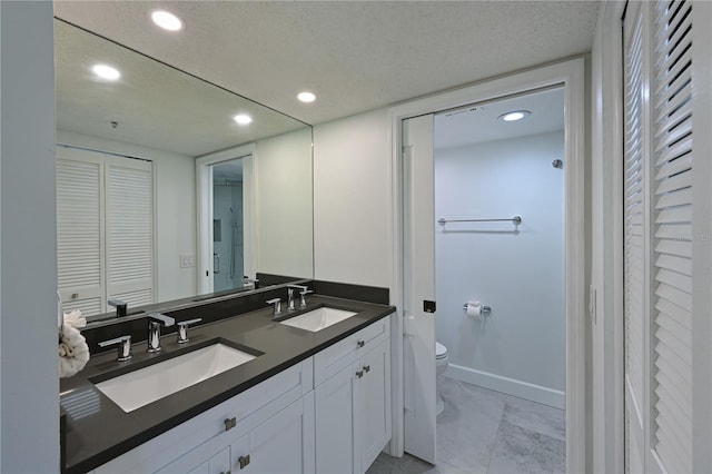 full bath featuring toilet, double vanity, a closet, and a sink