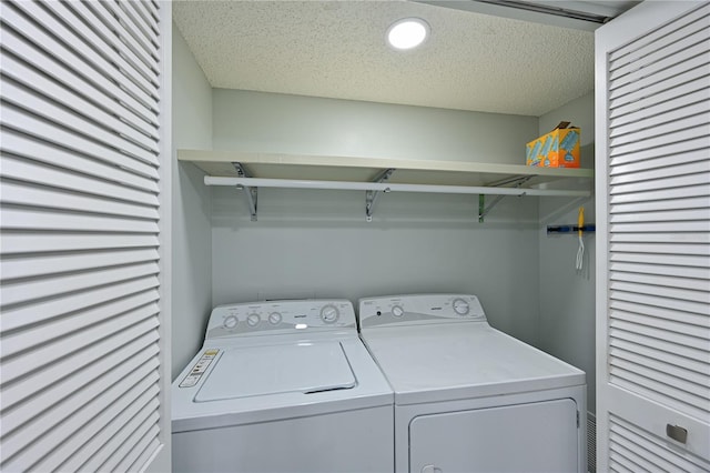 washroom with a textured ceiling, laundry area, and washer and clothes dryer