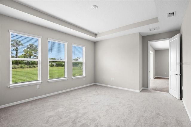 empty room with baseboards, visible vents, and light colored carpet