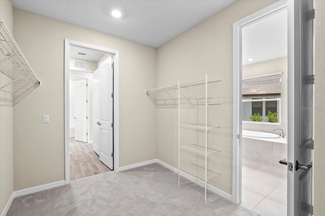 walk in closet with visible vents and light colored carpet