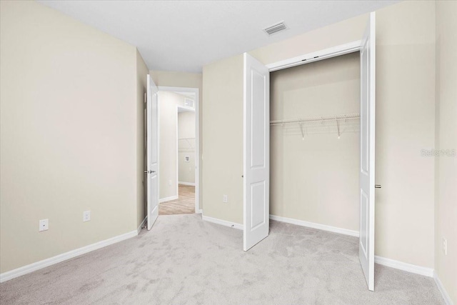 unfurnished bedroom with light carpet, baseboards, visible vents, and a closet