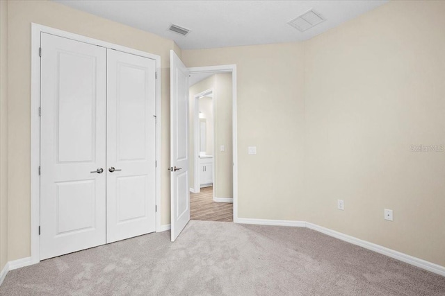 unfurnished bedroom featuring light colored carpet, a closet, visible vents, and baseboards