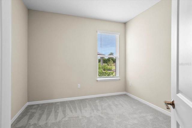 spare room featuring light carpet and baseboards