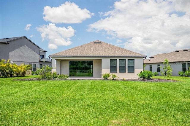 back of house with a shingled roof, a lawn, and stucco siding