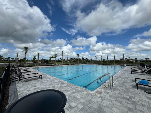 community pool with a patio and fence