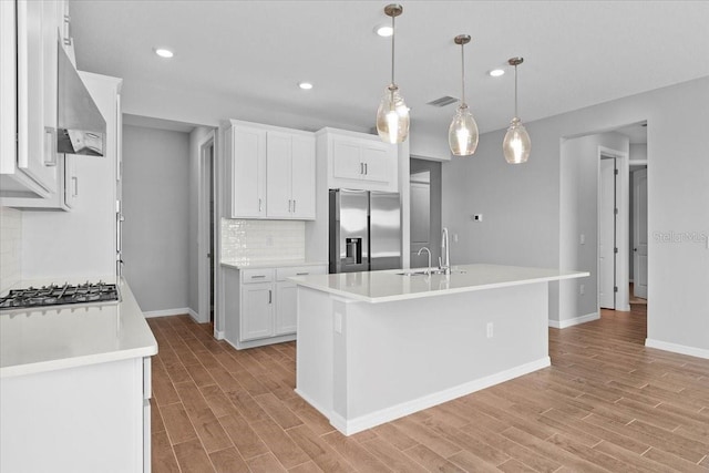 kitchen featuring light countertops, appliances with stainless steel finishes, and an island with sink