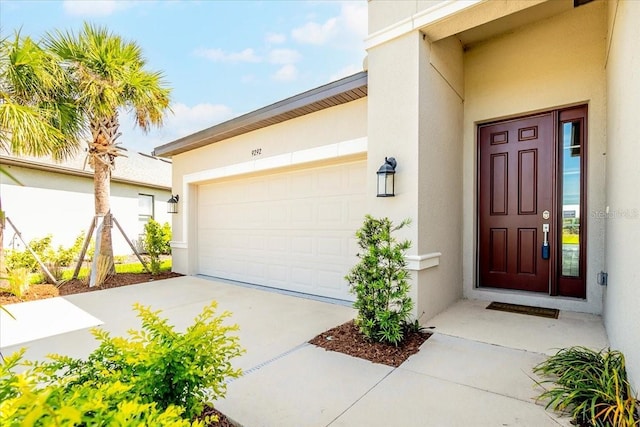 property entrance featuring a garage, driveway, and stucco siding