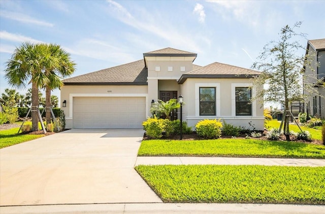 prairie-style house with an attached garage, concrete driveway, roof with shingles, stucco siding, and a front lawn