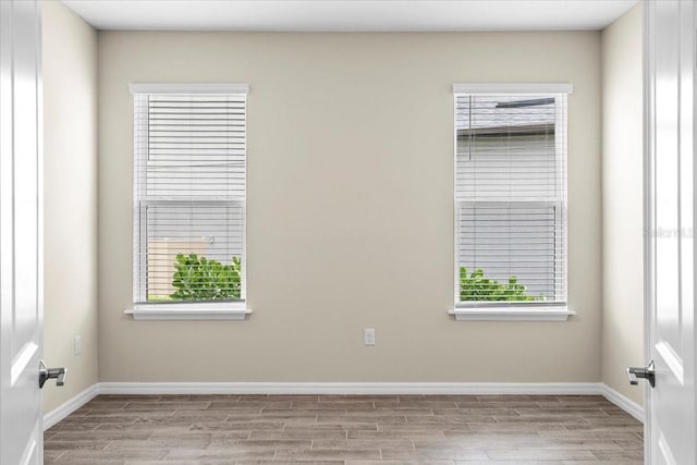 unfurnished room featuring a healthy amount of sunlight, light wood finished floors, and baseboards