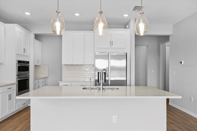 kitchen featuring stainless steel appliances, white cabinets, light countertops, and an island with sink