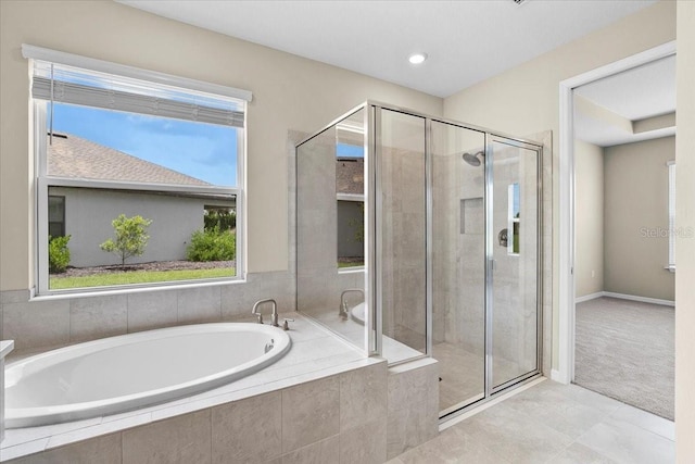 full bathroom with a garden tub, a shower stall, and baseboards