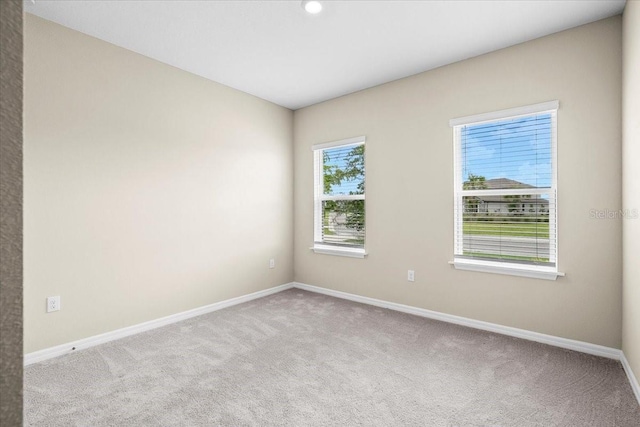 unfurnished room featuring light carpet and baseboards