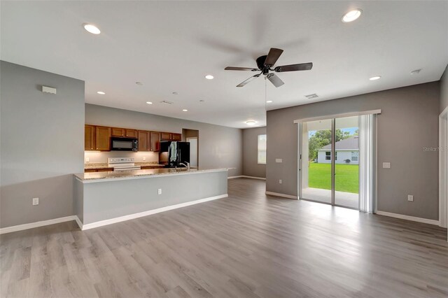 unfurnished living room featuring light hardwood / wood-style floors, sink, and ceiling fan