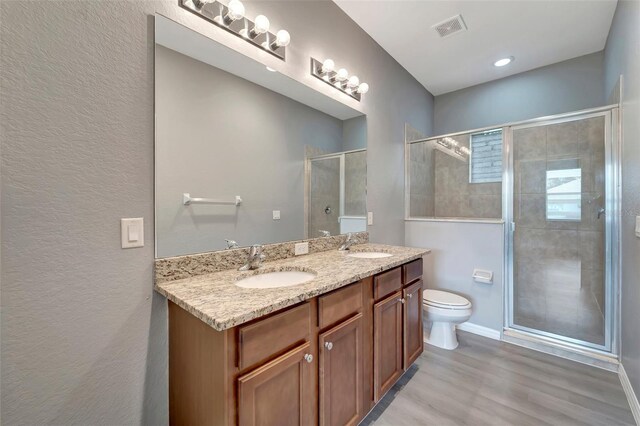 bathroom featuring double vanity, hardwood / wood-style floors, toilet, and an enclosed shower