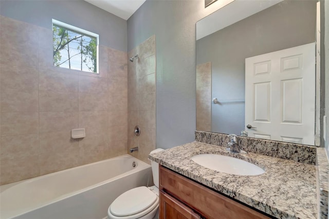 full bathroom featuring vanity, tiled shower / bath, and toilet