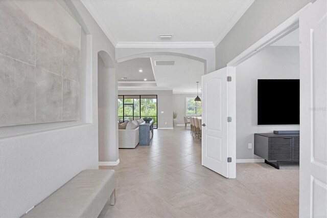 interior space featuring crown molding, light tile patterned floors, and a tray ceiling