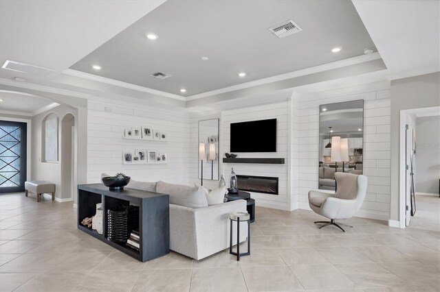 living room with a large fireplace, light tile patterned flooring, and ornamental molding