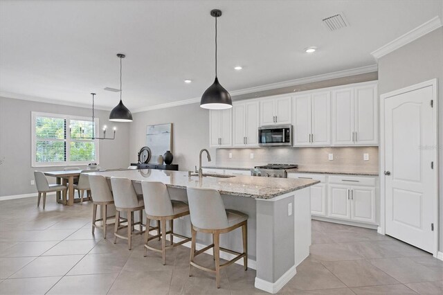 kitchen featuring range, white cabinetry, light stone counters, and a large island