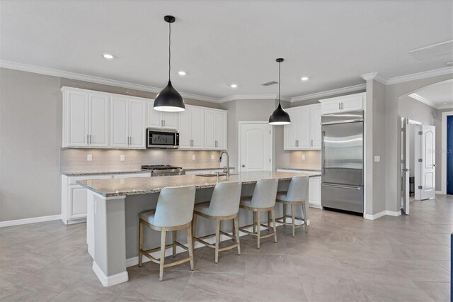 kitchen with stainless steel appliances, white cabinets, sink, light stone counters, and decorative backsplash