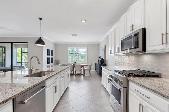 kitchen featuring hanging light fixtures, sink, light stone counters, appliances with stainless steel finishes, and backsplash