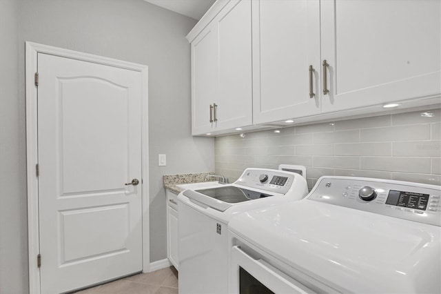 laundry room featuring cabinets, washing machine and dryer, sink, and light tile patterned floors