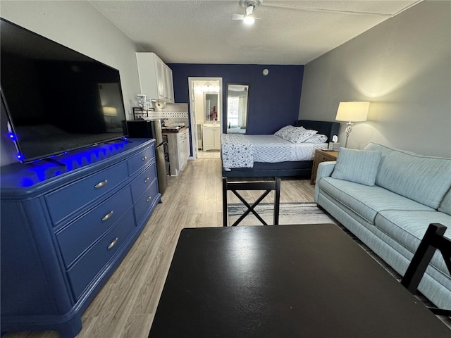 bedroom featuring light wood-type flooring, connected bathroom, and a textured ceiling