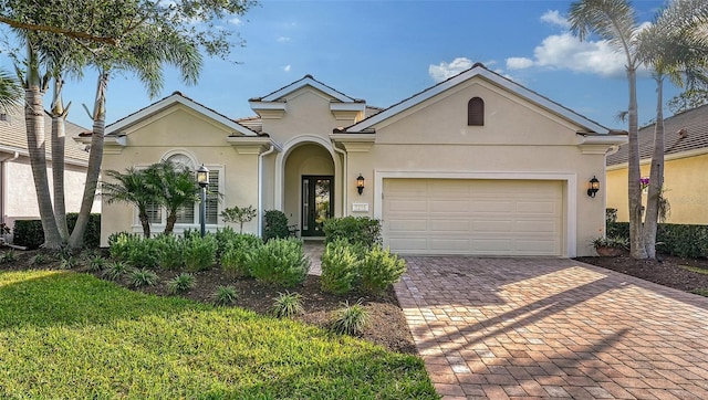 view of front of home featuring decorative driveway, an attached garage, and stucco siding