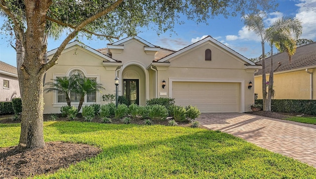 view of front of property with an attached garage, a front yard, decorative driveway, and stucco siding