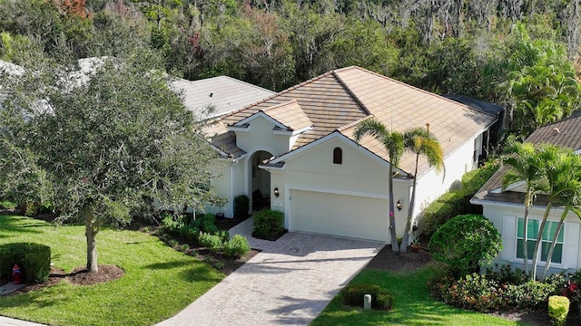 view of front of property with a garage, a front yard, decorative driveway, and stucco siding