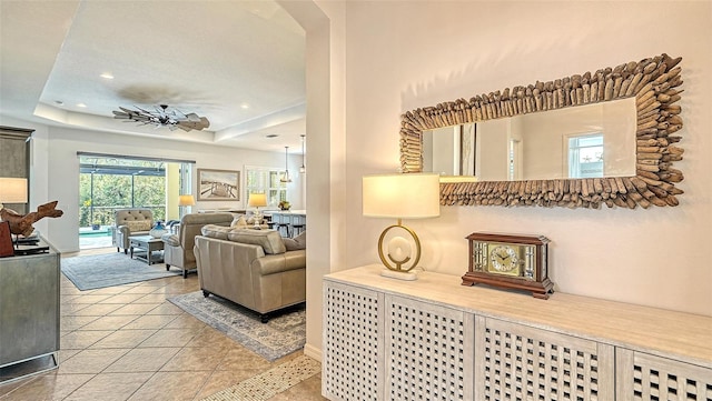 living room featuring light tile patterned floors, a raised ceiling, and ceiling fan