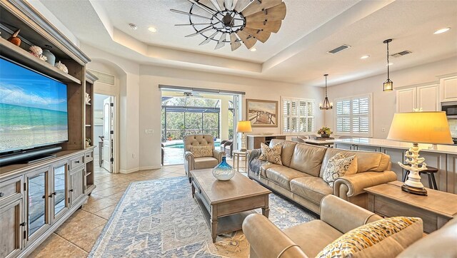 living room featuring a healthy amount of sunlight, light tile patterned floors, and a tray ceiling