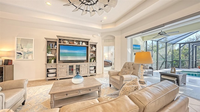 living room featuring light tile patterned flooring, a raised ceiling, and ceiling fan