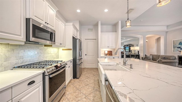 kitchen featuring pendant lighting, white cabinets, backsplash, and stainless steel appliances