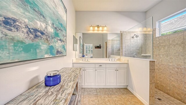 bathroom featuring dual vanity, tile patterned flooring, and a tile shower