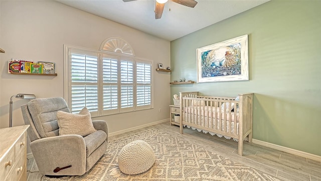 bedroom with a crib, light wood-type flooring, and ceiling fan