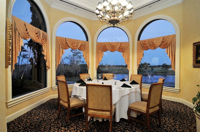 carpeted dining space featuring a water view, ornamental molding, and an inviting chandelier