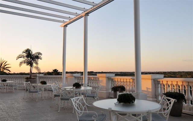 patio terrace at dusk featuring a pergola and a water view