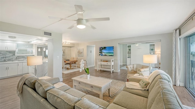 living room featuring light hardwood / wood-style floors, sink, and ceiling fan