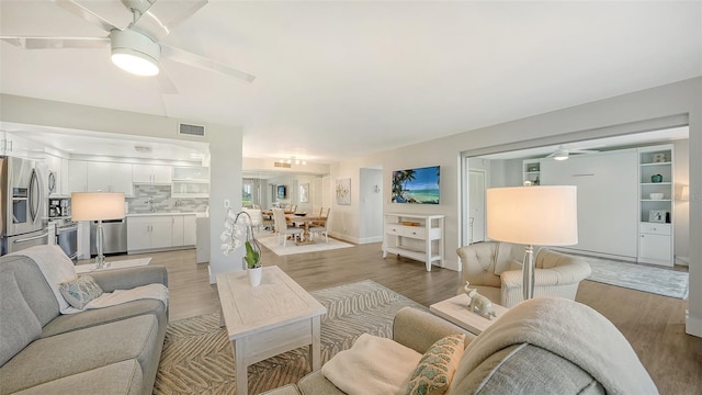 living room with light hardwood / wood-style floors and ceiling fan