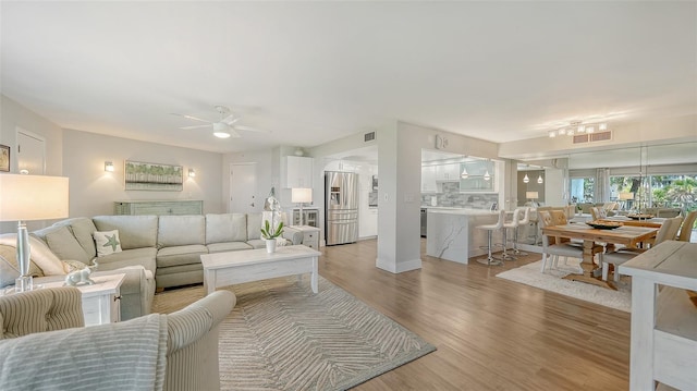 living room with light hardwood / wood-style floors and ceiling fan