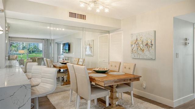 dining space with wood-type flooring and a notable chandelier