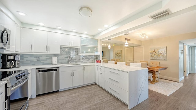 kitchen featuring stainless steel appliances, light hardwood / wood-style floors, sink, and kitchen peninsula