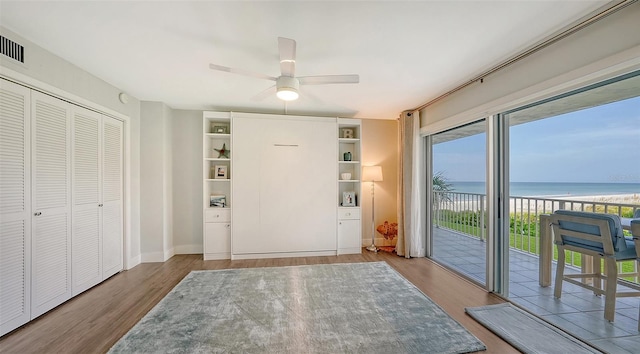 entrance foyer with a water view, wood-type flooring, ceiling fan, and a healthy amount of sunlight